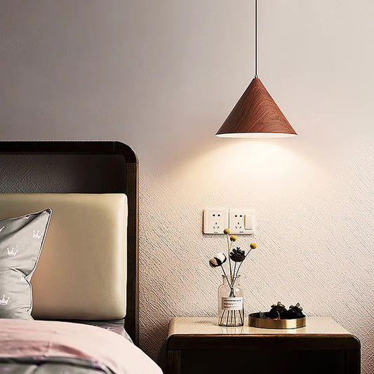 Metal pendant light with wood grain finish hanging above bedside table.