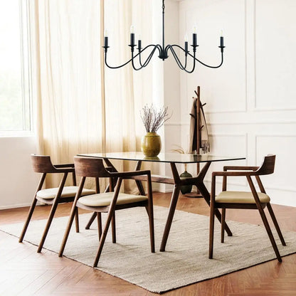 A black 6-light chandelier in a minimalist dining area featuring a glass table and modern wooden chairs.