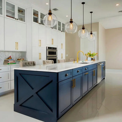 Modern kitchen with a large island illuminated by three clear glass globe pendant lights.