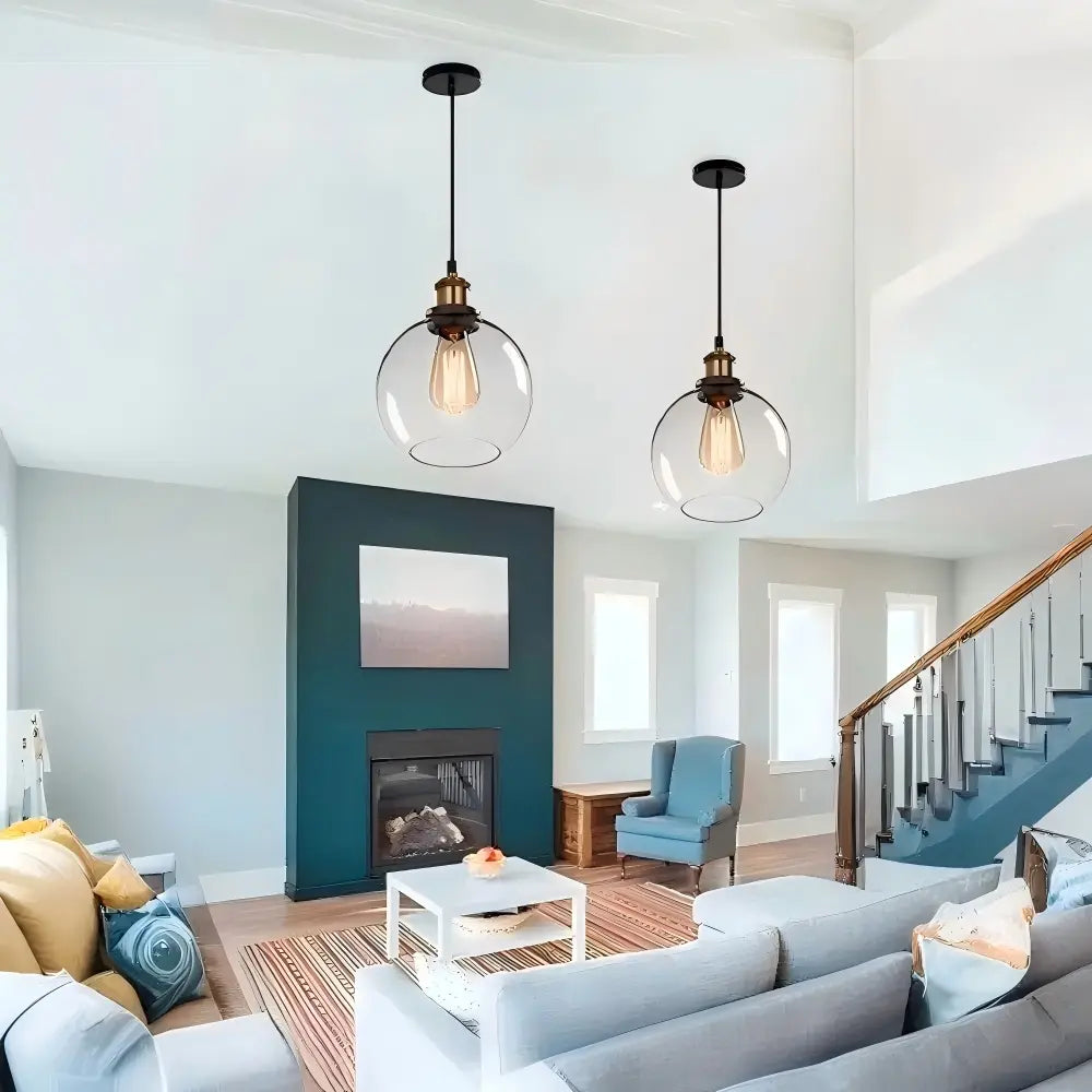 Two clear glass globe pendant lights illuminating a spacious modern living room with high ceilings and a fireplace.
