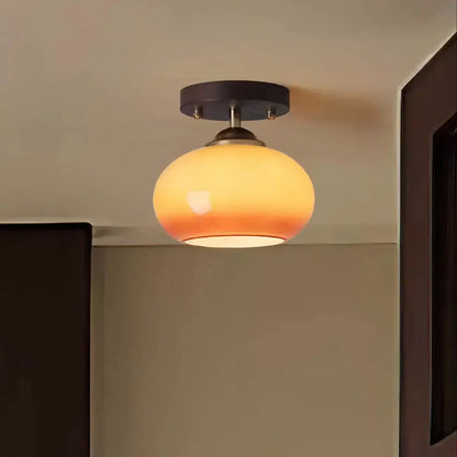 Close-up view of a modern walnut wood ceiling light featuring a spherical opal glass shade, highlighting craftsmanship.