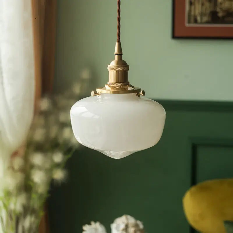 Close view of opaque white glass pendant shade with brass-tone metal hardware