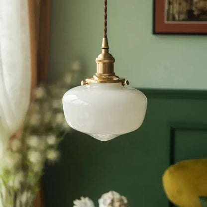 Close view of opaque white glass pendant shade with brass-tone metal hardware