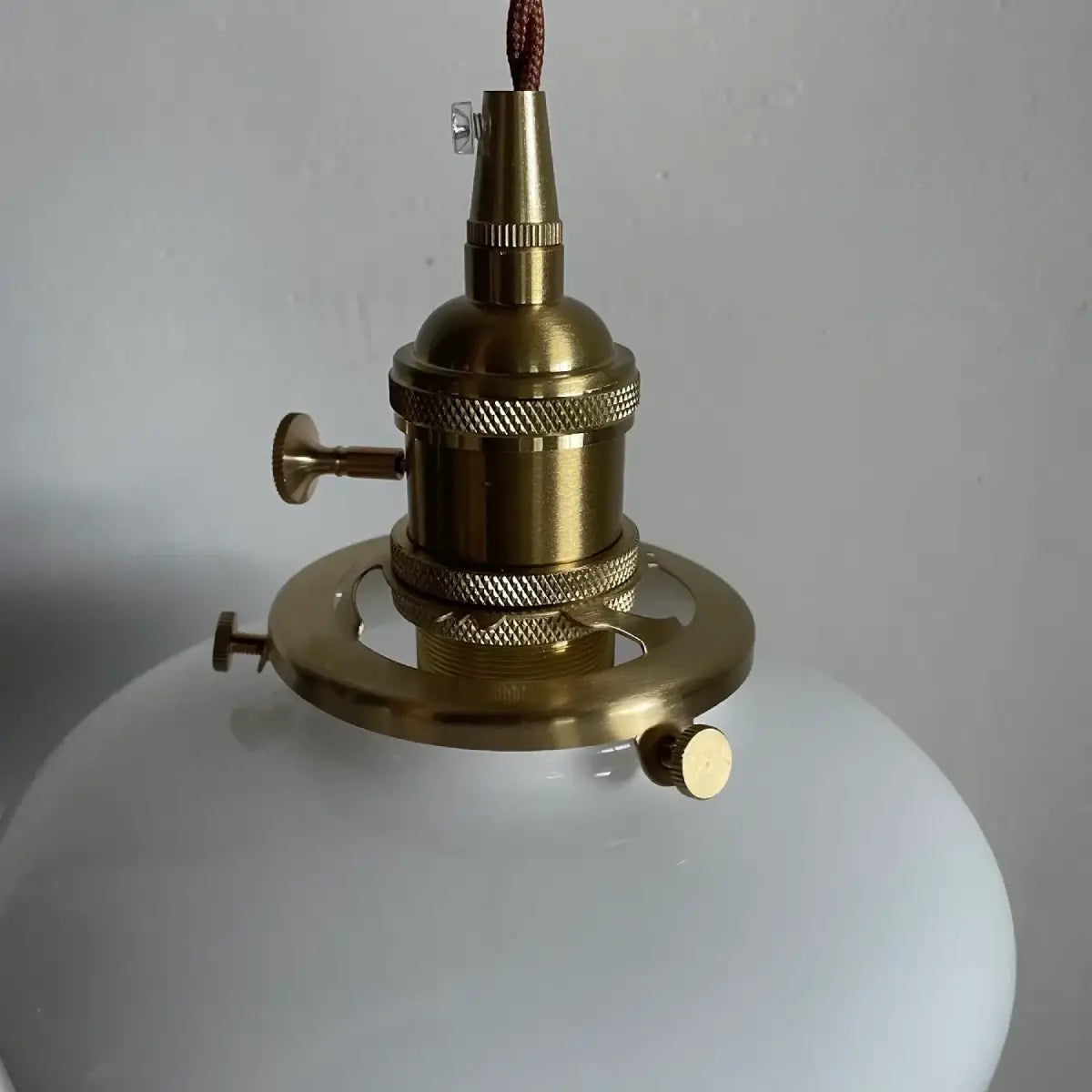 Milk glass schoolhouse pendant light shown from a front angle showing the twisted cord