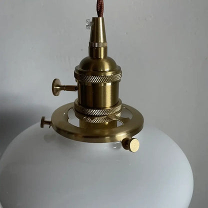 Milk glass schoolhouse pendant light shown from a front angle showing the twisted cord