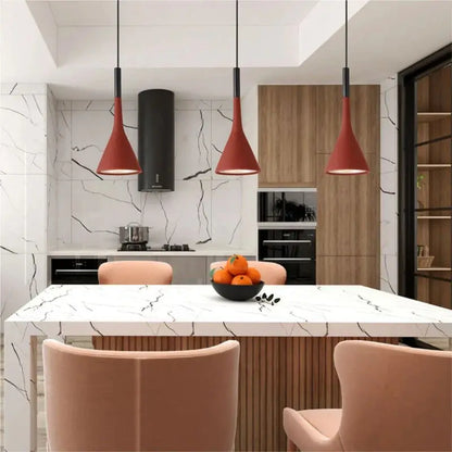 Three striking red modern pendant lights over a white marble kitchen island in a stylish kitchen, adding a vibrant pop of colour to kitchen designs