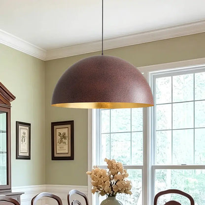 Textured rust-brown dome pendant above a dining area with pale green walls, framed artwork, and large windows.