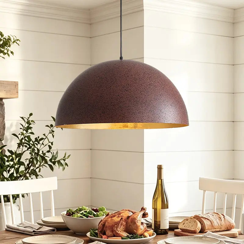 Rust-brown dome pendant hanging above a set dining table with white chairs in a bright, white-paneled room.