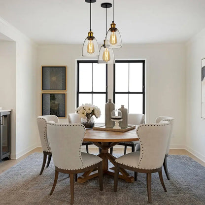 Vintage glass pendant lights hanging above a wooden dining table in a bright, modern dining room.