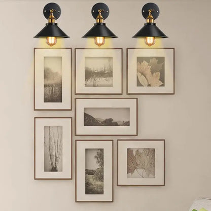 A pair of black wall sconces used as modern gallery lighting, perfectly illuminating wall art and photos.