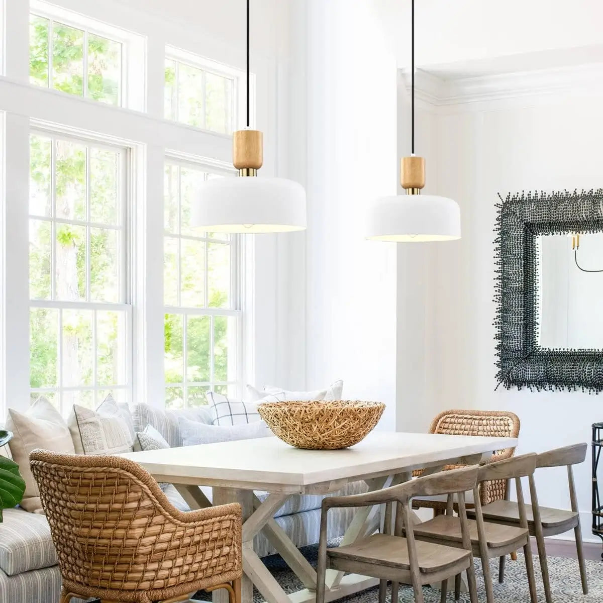 Two white pendant lights hanging in a bright dining area with natural textures